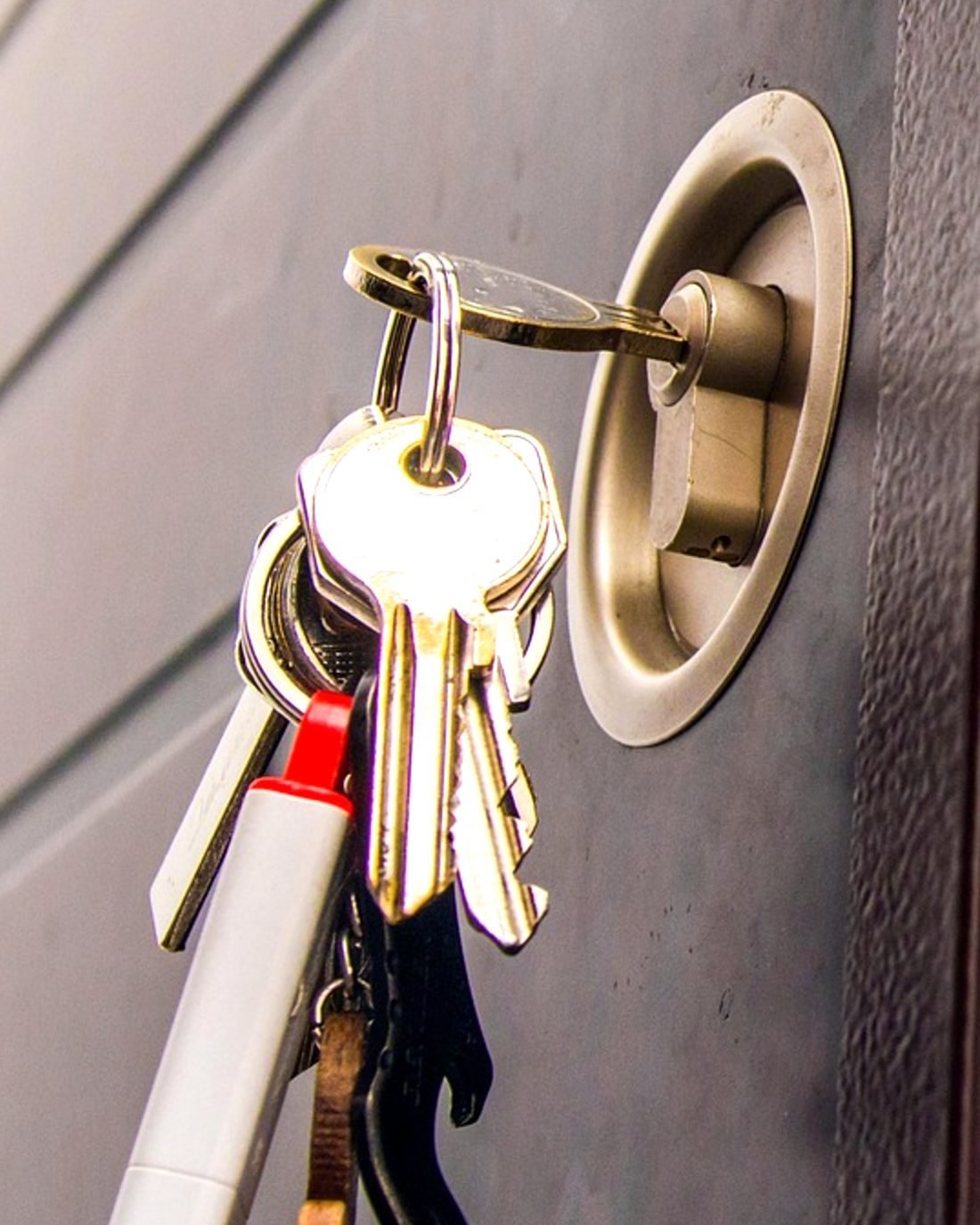 Un trousseau de clés suspendu à la clé restée dans le cylindre d’une porte en acier grise