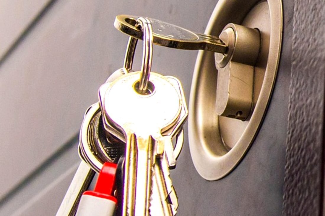 A set of keys left in the cylinder of a grey steel door