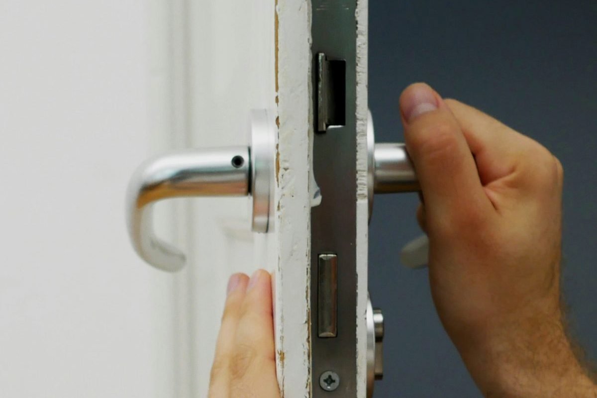 Un technicien posant une serrure à mortaise dans le chant d’une porte blanche